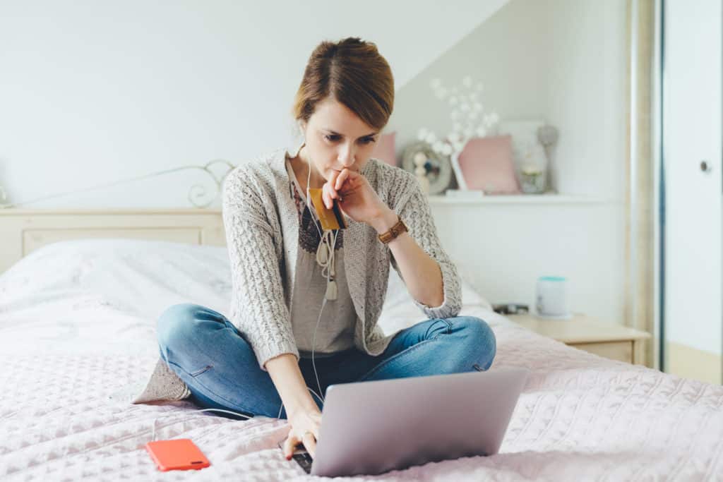 Young woman in the bedroom using laptop for planning the home finances