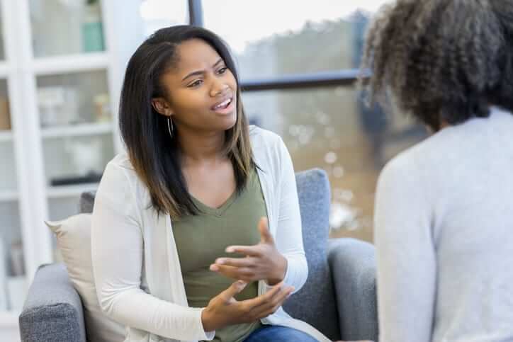 Young African American woman gestures while discussing problems with a female mental health professional.