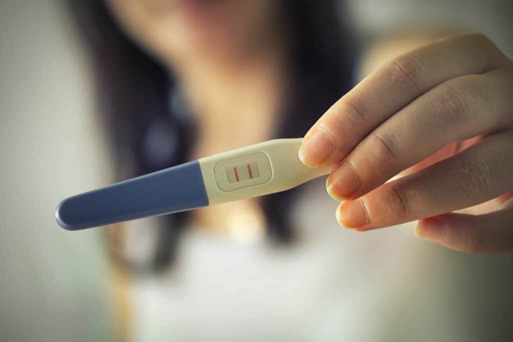 Girl out of focus showing positive pregnancy test